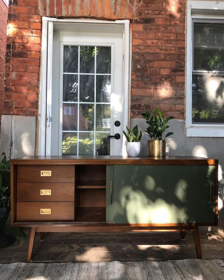 a sideboard with plants on it in front of a brick building