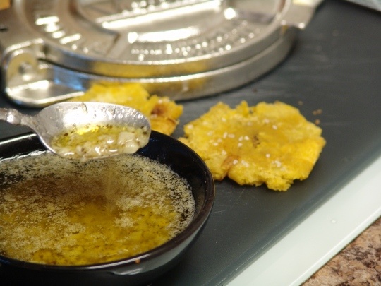 a person spooning some food out of a black bowl on a stove top next to other foods