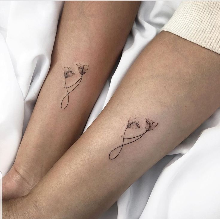 two people with matching tattoos on their legs, one is holding the other's hand