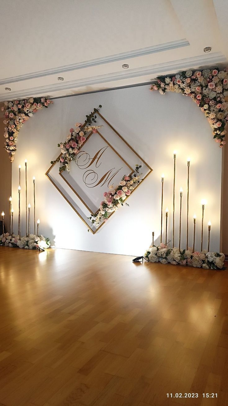 an empty room with candles and flowers on the wall next to a sign that says monogram