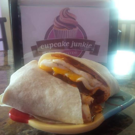 a burrito sitting on top of a plate next to a cupcake