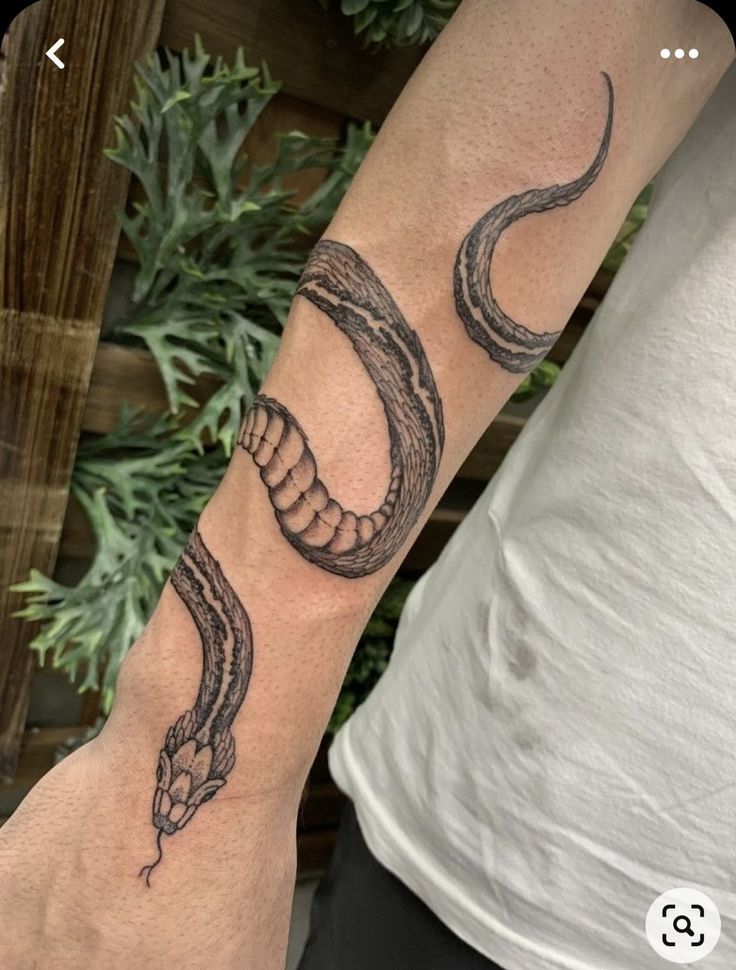 a man's arm with a snake tattoo on it