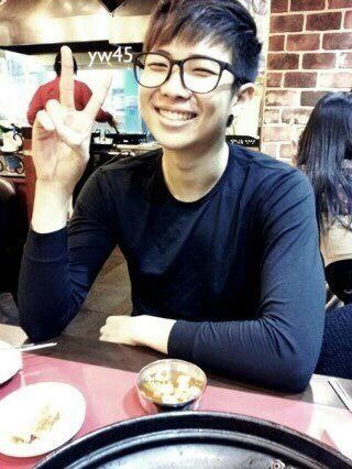 a man sitting at a table with food in front of him and making the peace sign