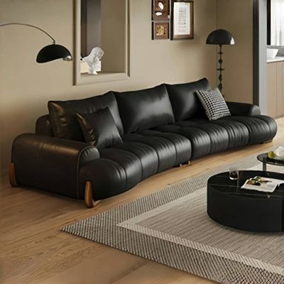 a living room filled with black furniture and lots of windows