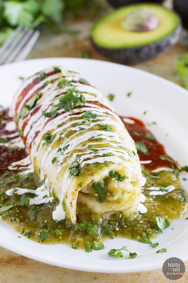 an enchilada on a plate with sauce and avocado