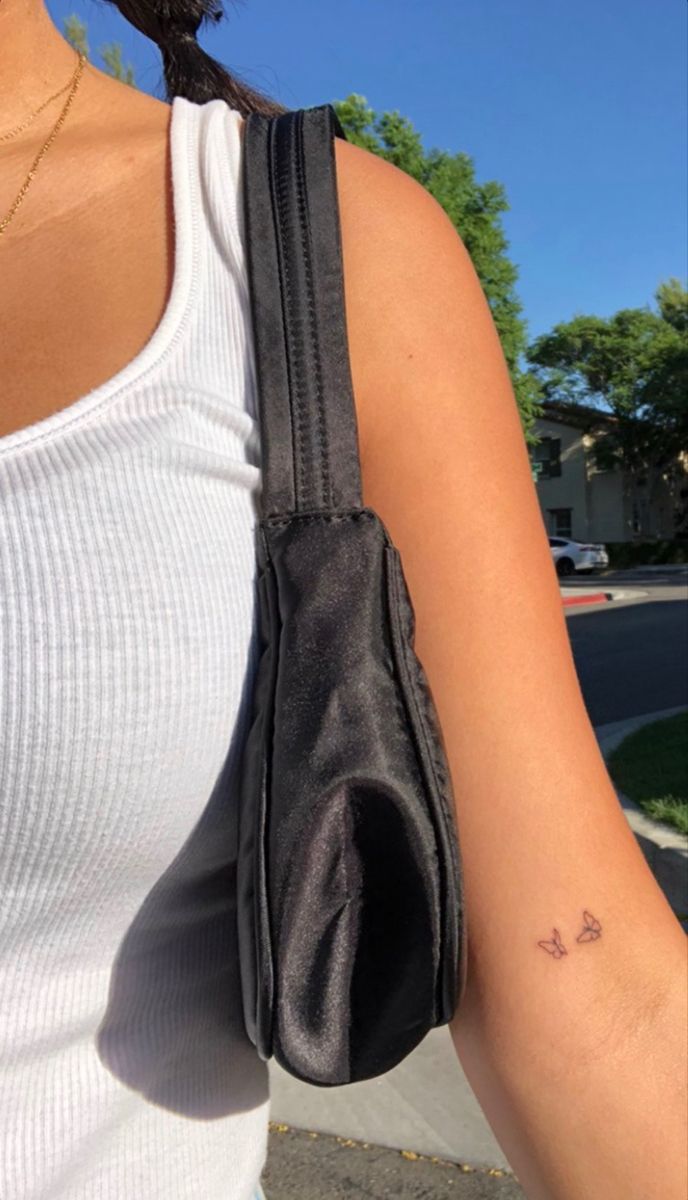 a woman with a small tattoo on her left arm holding onto a black handbag