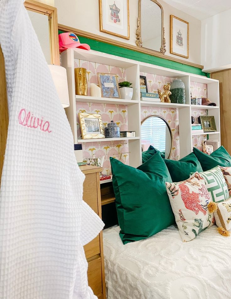 a white bed topped with lots of pillows next to a book shelf filled with books