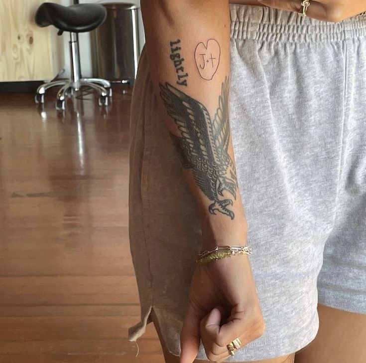 a woman with a tattoo on her arm pointing to the side while standing in a room