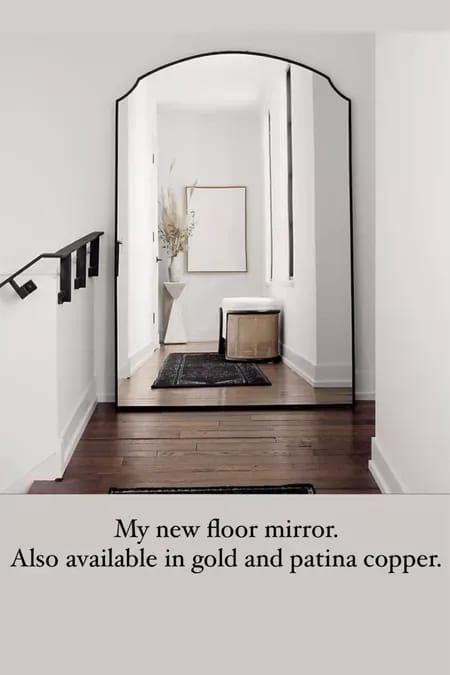 a mirror sitting on the side of a white wall next to a wooden floor and stairs