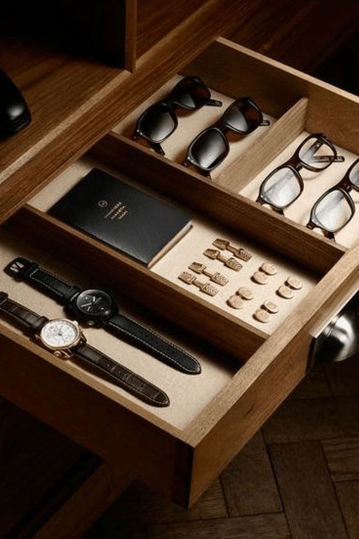 an open drawer with glasses and other items in it on a wooden floor next to a computer mouse