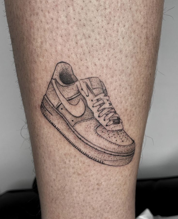 a tattoo on the leg of a person with a nike sneaker shoe in black ink