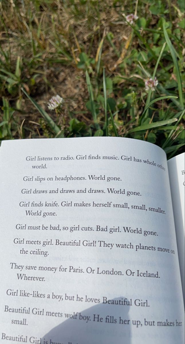 an open book sitting on top of a grass covered field