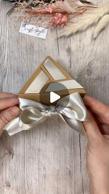 someone is opening up a gift box with a bow tie on the top and another person holding it in their hands