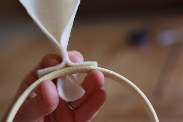 a hand holding a piece of white material in it's palm with a loop around it