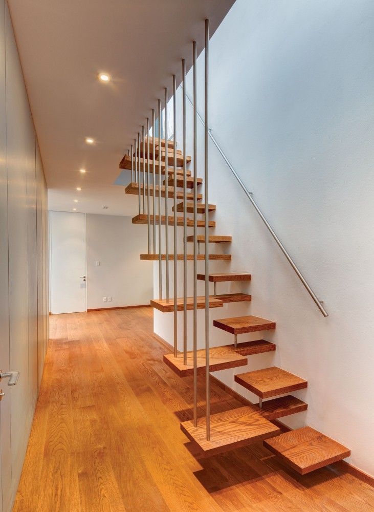 there is a wooden stair case in the room with wood flooring and white walls