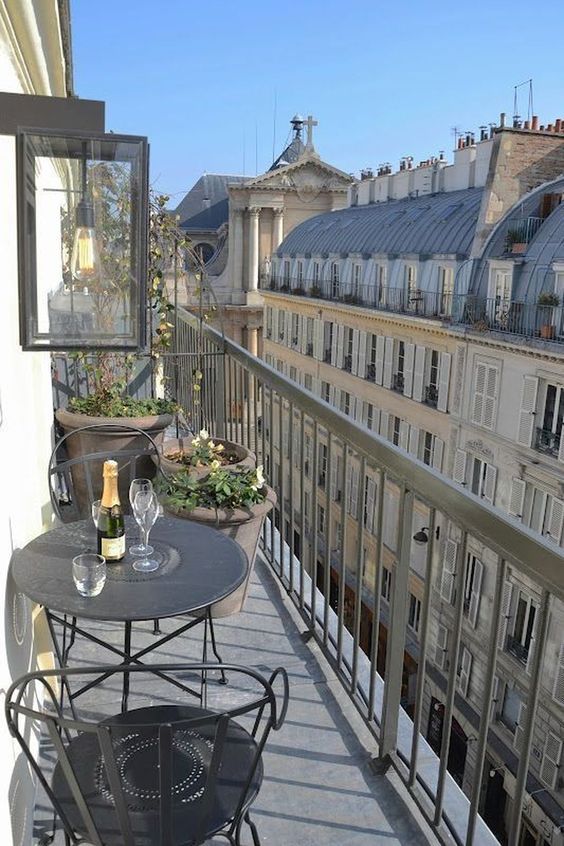 a balcony with tables and chairs on the side of it, overlooking an old building