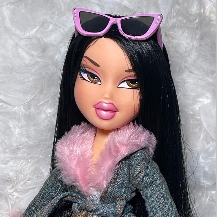 a close up of a doll wearing sunglasses and a fur stole around her neck on a white background