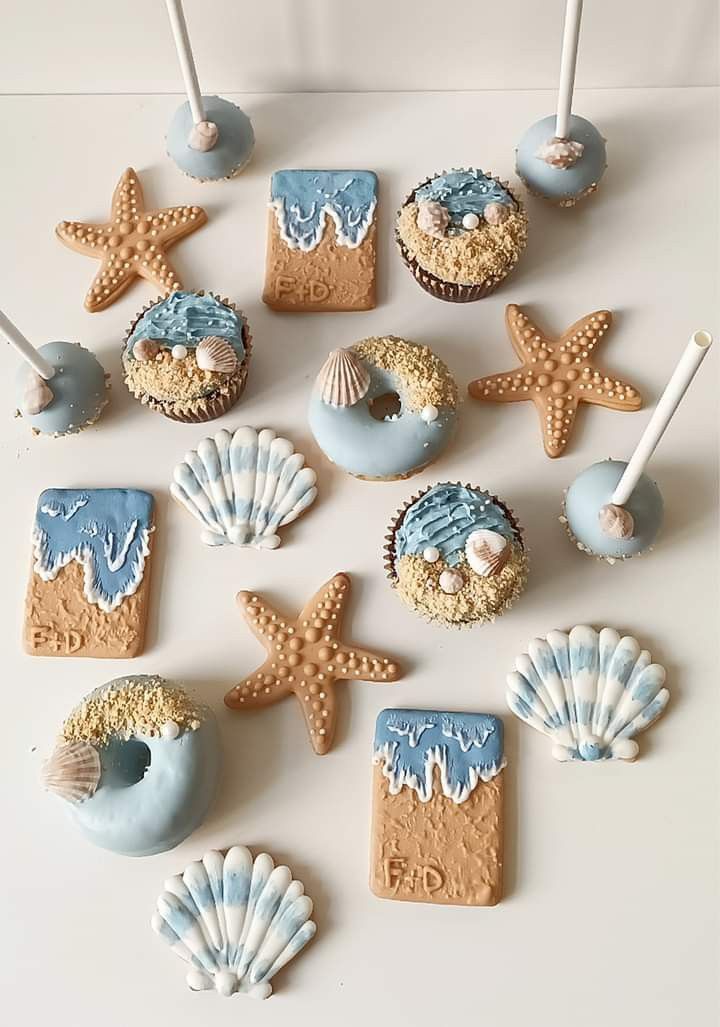 some cupcakes and cookies are arranged in the shape of seashells on a table