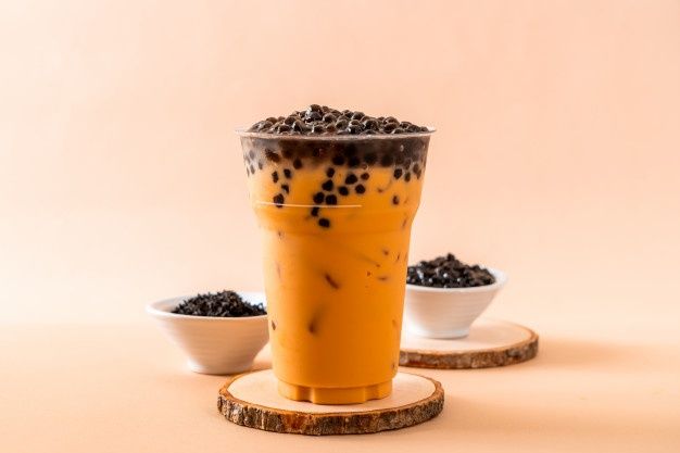 an orange drink with chocolate sprinkles in it and two small white bowls