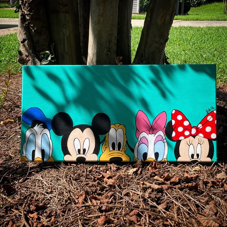 an image of mickey mouse and friends painted on a sign in front of a tree