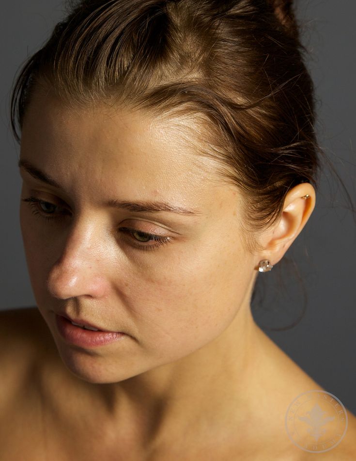 a close up of a woman with her eyes closed looking down at something in the distance