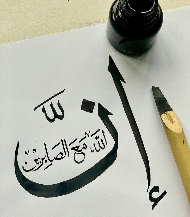 an arabic calligraphy is written on a sheet of paper with a fountain pen next to it