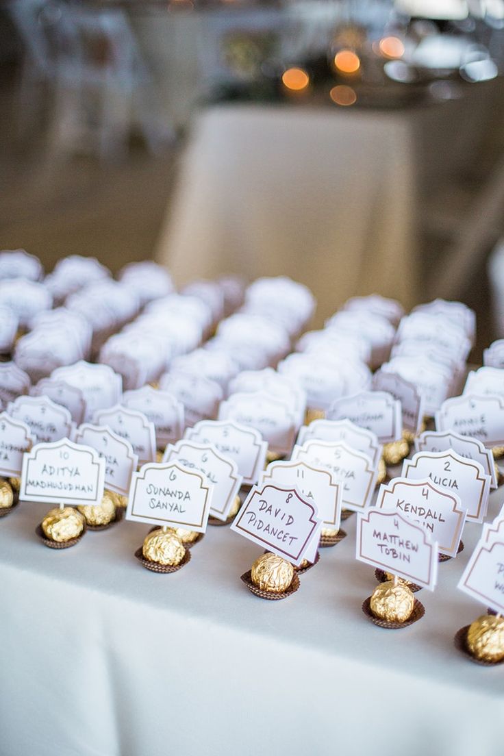 there are many small cupcakes on the table with name tags attached to them