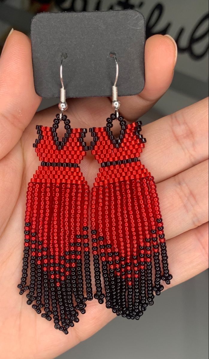 a pair of red and black beaded earrings with tassels hanging from it