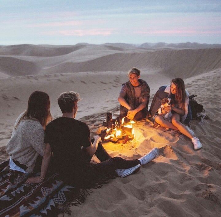 four people sitting around a campfire in the desert