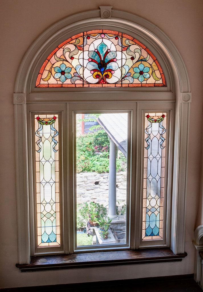 a stained glass window in the corner of a room with an arched door and bench