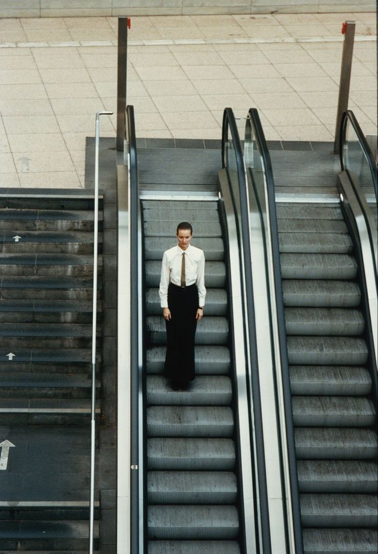 a man standing at the bottom of an escalator with his hands in his pockets