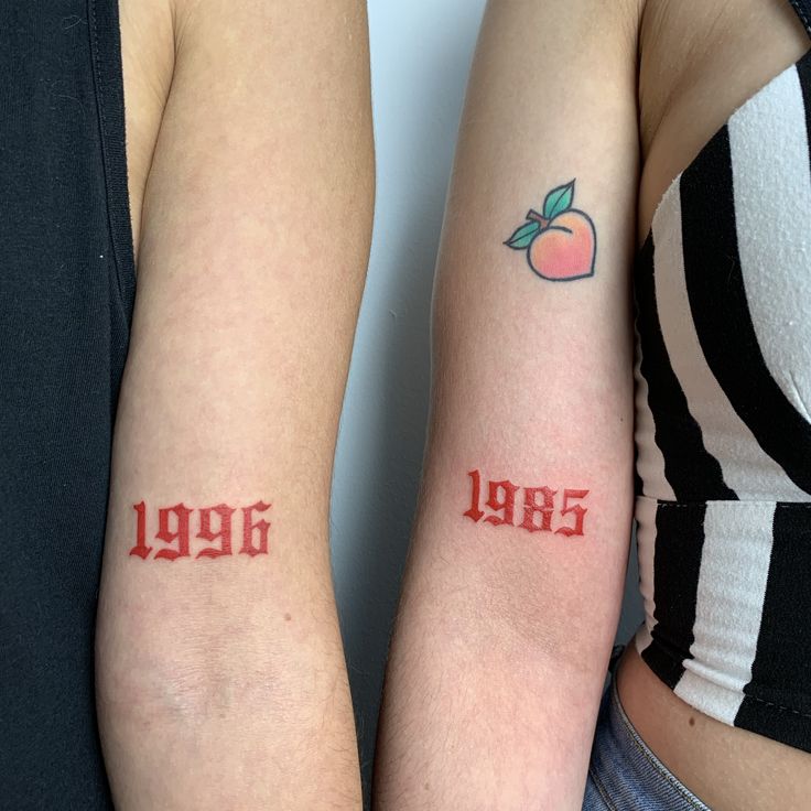 two people with matching tattoos on their arms, one has an apple and the other has numbers