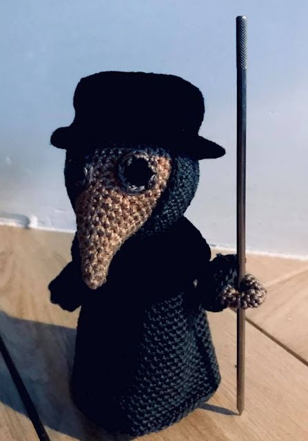 a small crocheted animal wearing a top hat and holding a cane on a wooden table