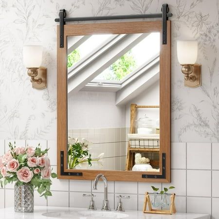 a bathroom sink sitting under a mirror next to a vase with flowers on top of it