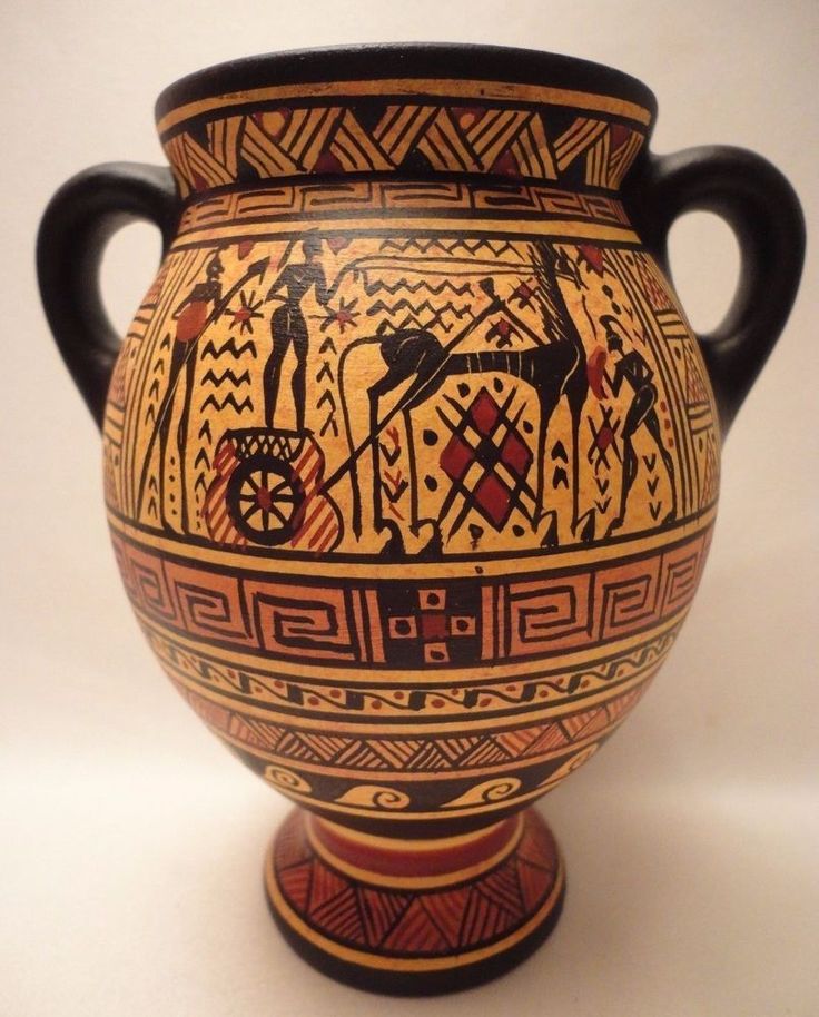 an old vase with designs on it sitting on a white table next to a wall