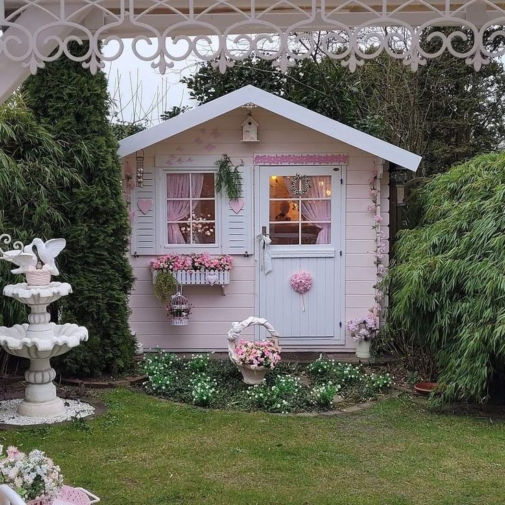 a little pink house with flowers in the front yard