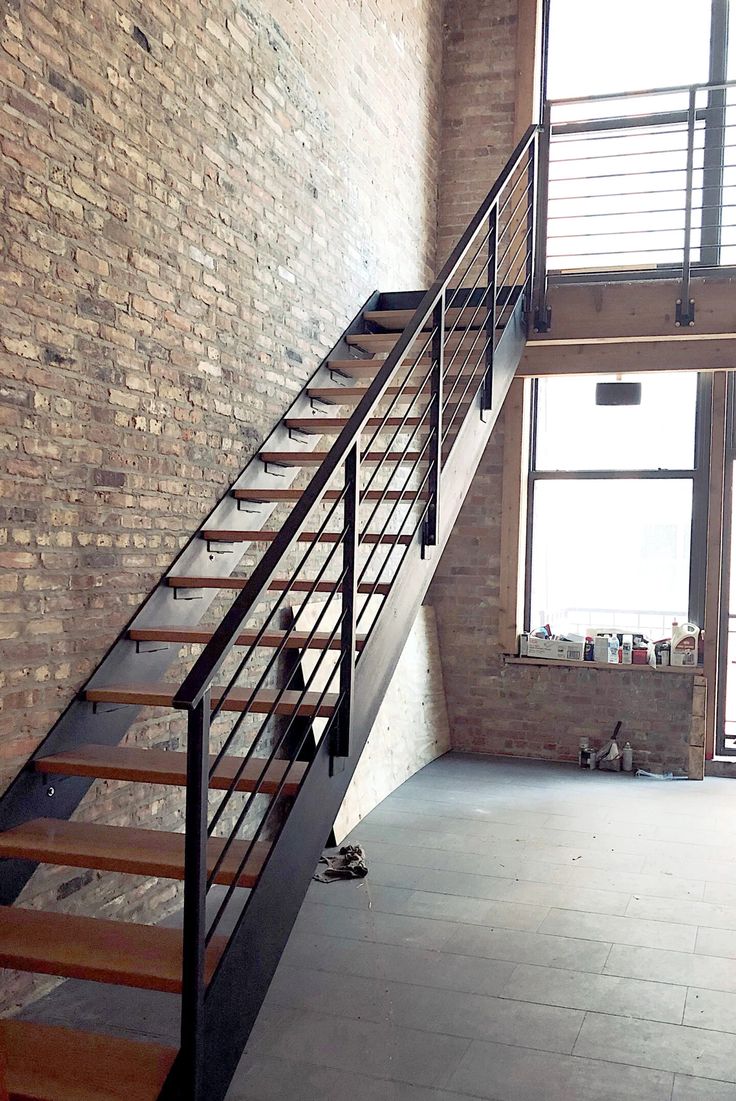 there is a stair case in the middle of an empty room next to a brick wall