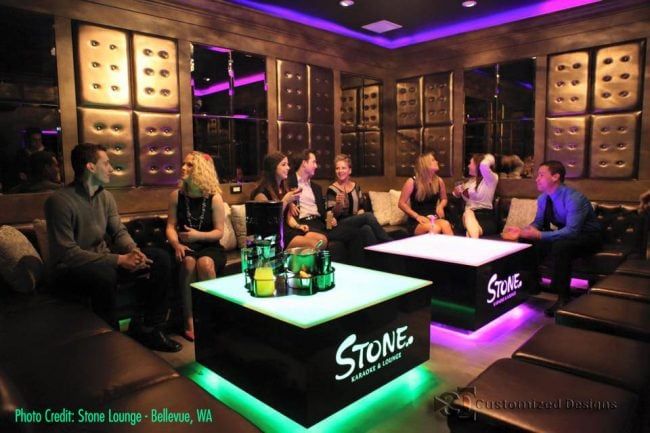 a group of people sitting around in a room with neon lights on the walls and floor