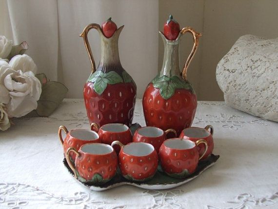 a set of four strawberry shaped cups and saucers on a tray with matching plates