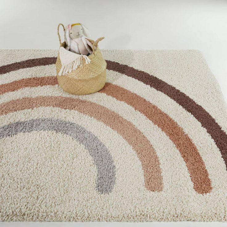 a rug with a basket on top of it next to a stuffed animal in the middle