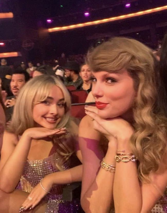 two beautiful women sitting next to each other at a concert