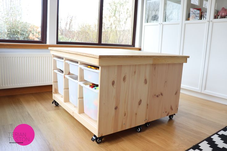 a kitchen island made out of plywood with storage bins on the top and wheels