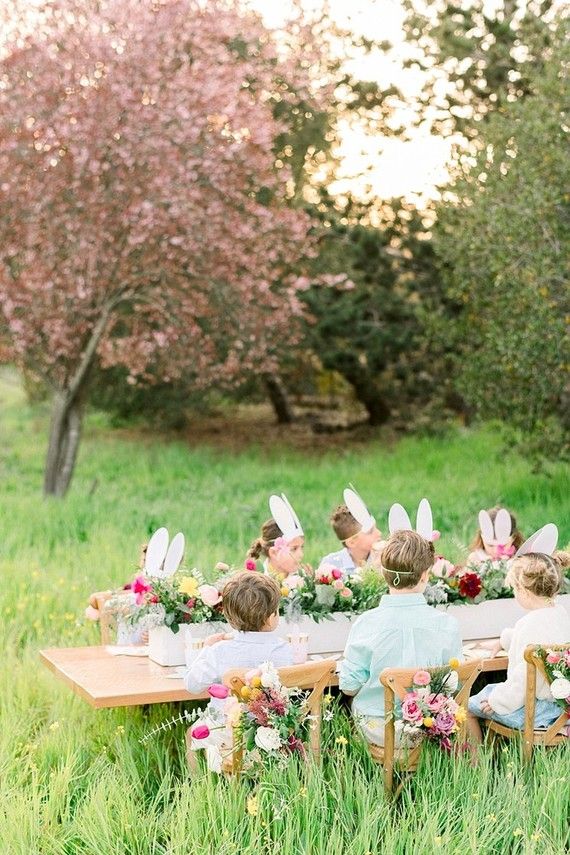 a group of people sitting at a table with bunny ears on their heads and flowers in front of them