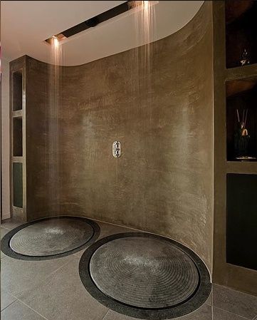 a bathroom with two circular rugs on the floor in front of a large shower