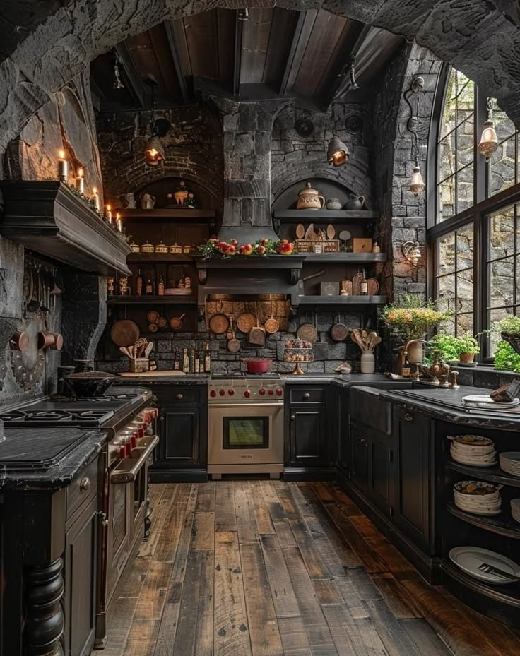 an old fashioned kitchen with wood floors and stone walls, along with black cabinets and appliances