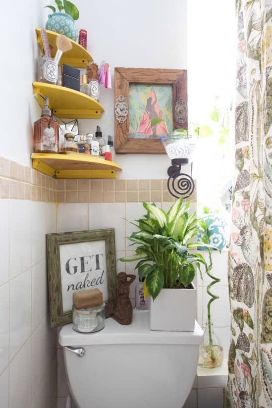 a bathroom with a toilet, potted plant and pictures on the wall above it