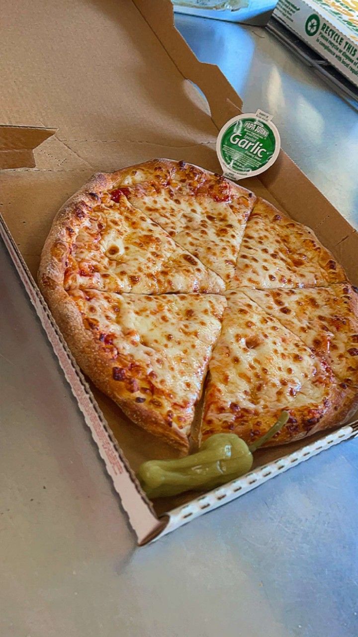 a pizza in a box on a table with a slice missing from it and some pickles