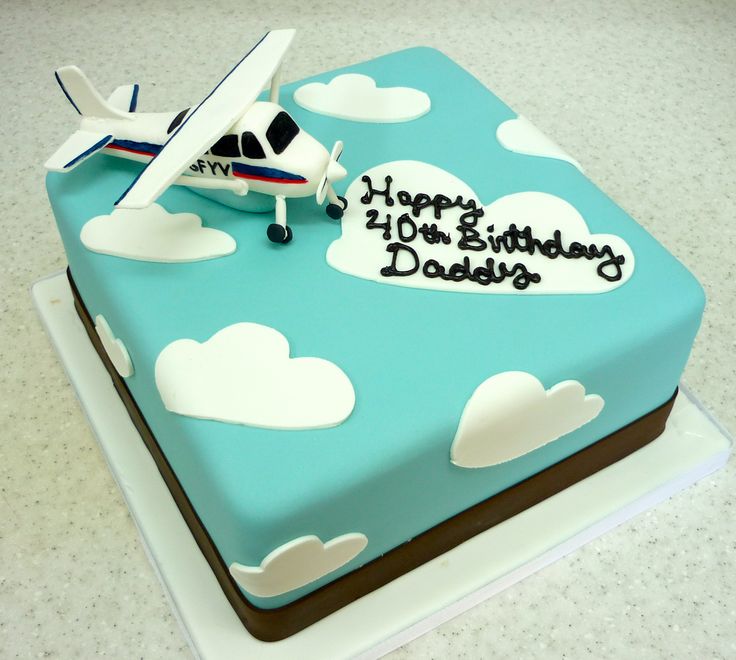 a birthday cake with an airplane and clouds on it