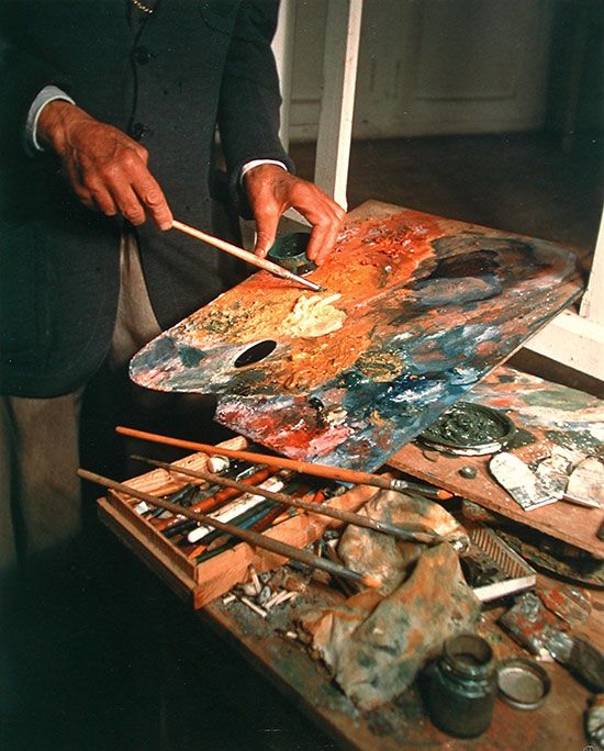 a man in a suit painting on an easel