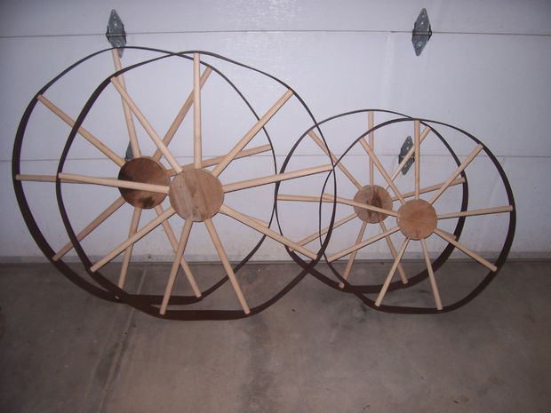 two wooden wheels sitting next to each other on the floor in front of a white wall